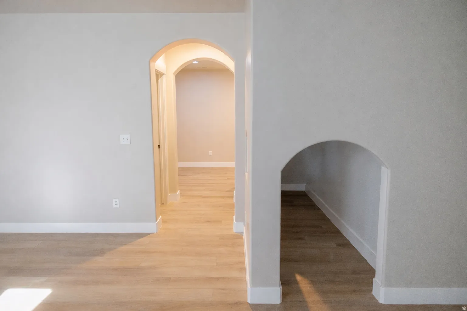 Empty room featuring arched walkways and light wood-style floors