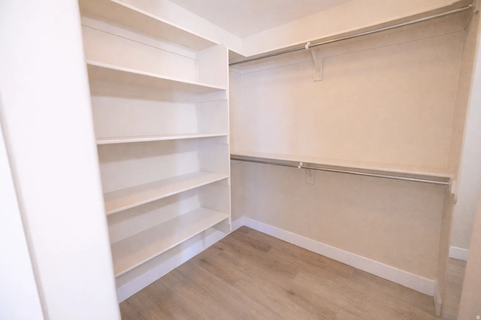 Walk in closet with light wood-style flooring