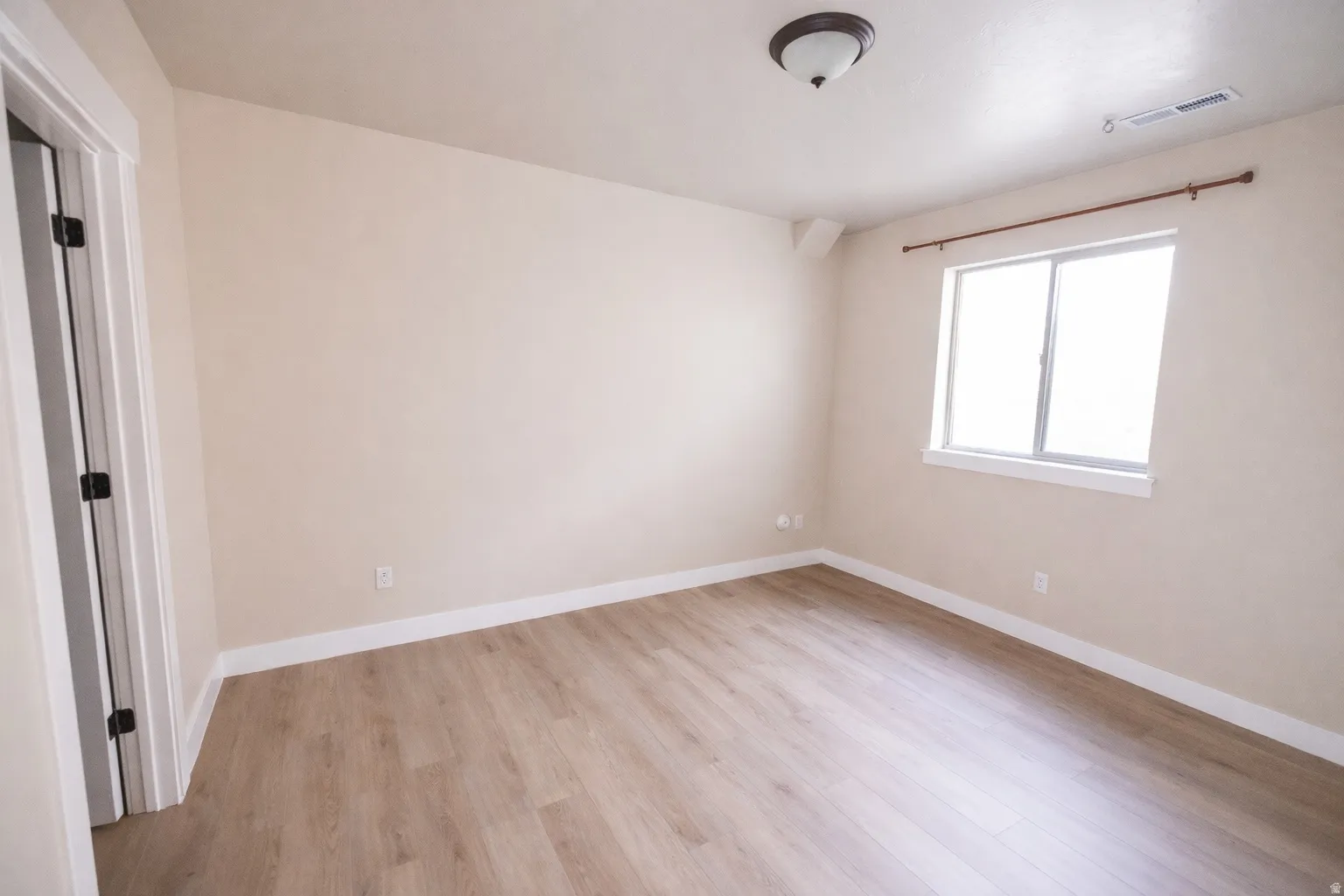 Empty room with light wood-style flooring and baseboards