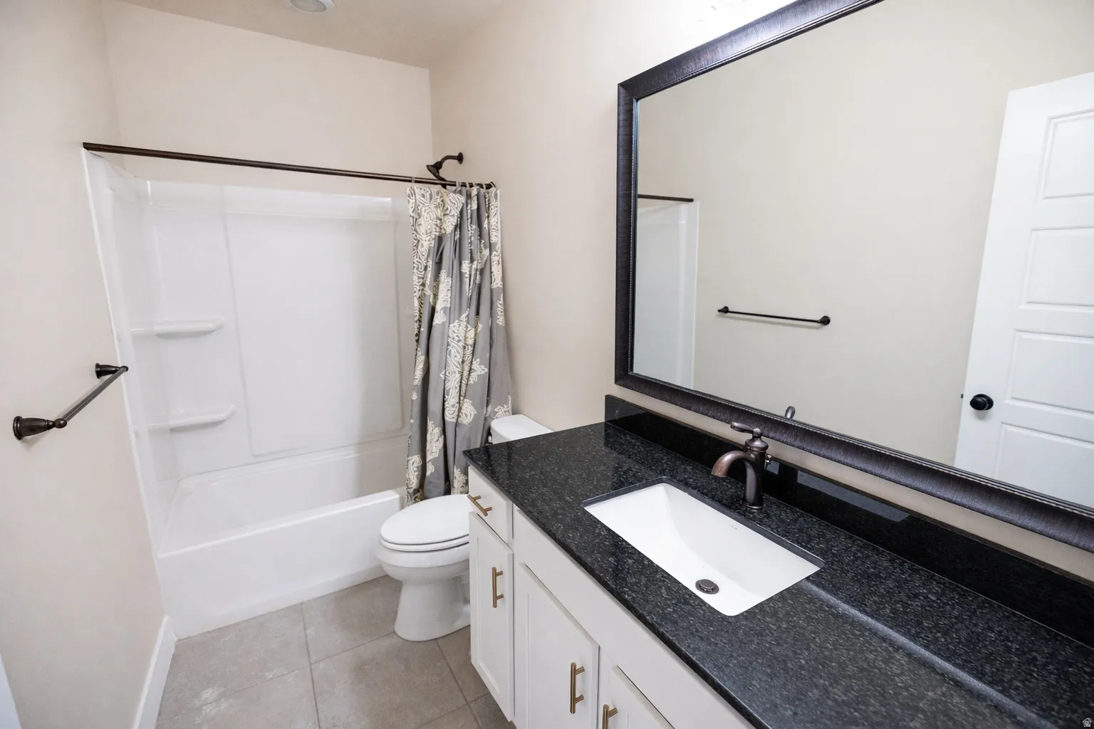 Full bathroom with vanity, shower / tub combo with curtain, and light tile patterned floors
