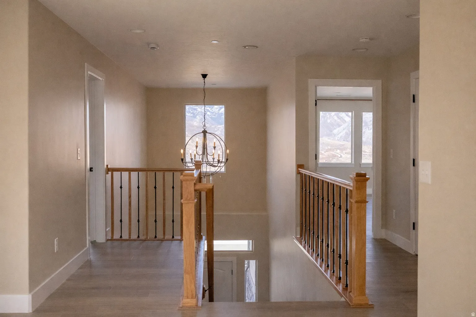Stairway with suspended lighting, wood finished floors, and healthy amount of natural light
