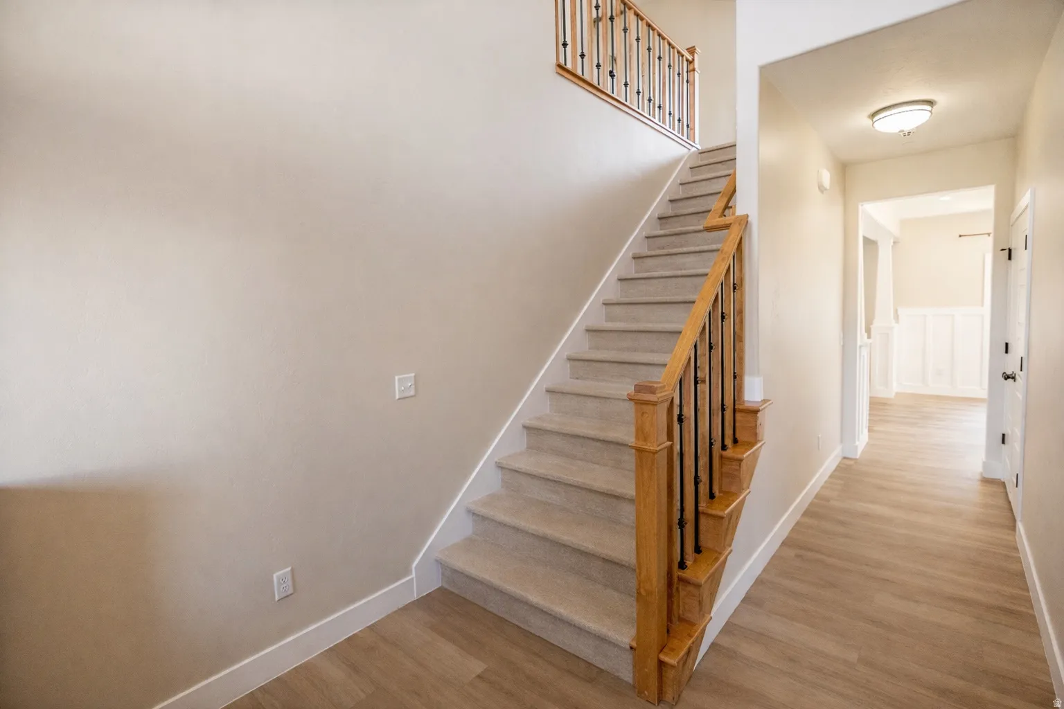 Entryway featuring a staircase with wood railing, brand-new luxury waterproof vinyl flooring and a hallway leading to the main living area