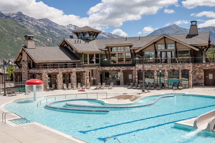 Community pool featuring a water slide, a mountain view, a patio area, a water play area, and a balcony