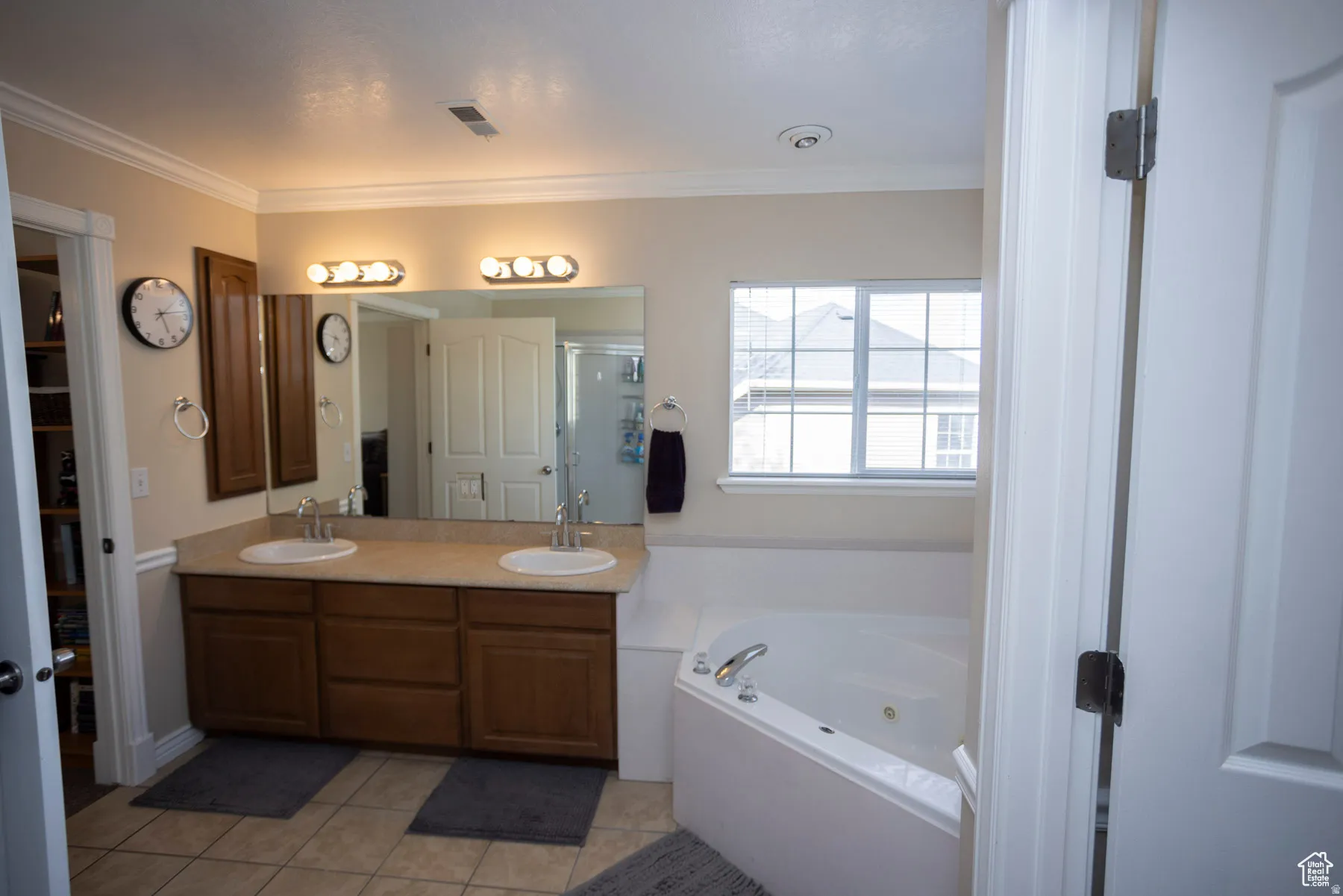 Primary Bedroom Full bath featuring double vanity, light tile patterned flooring, a garden tub, crown molding, and a stall shower