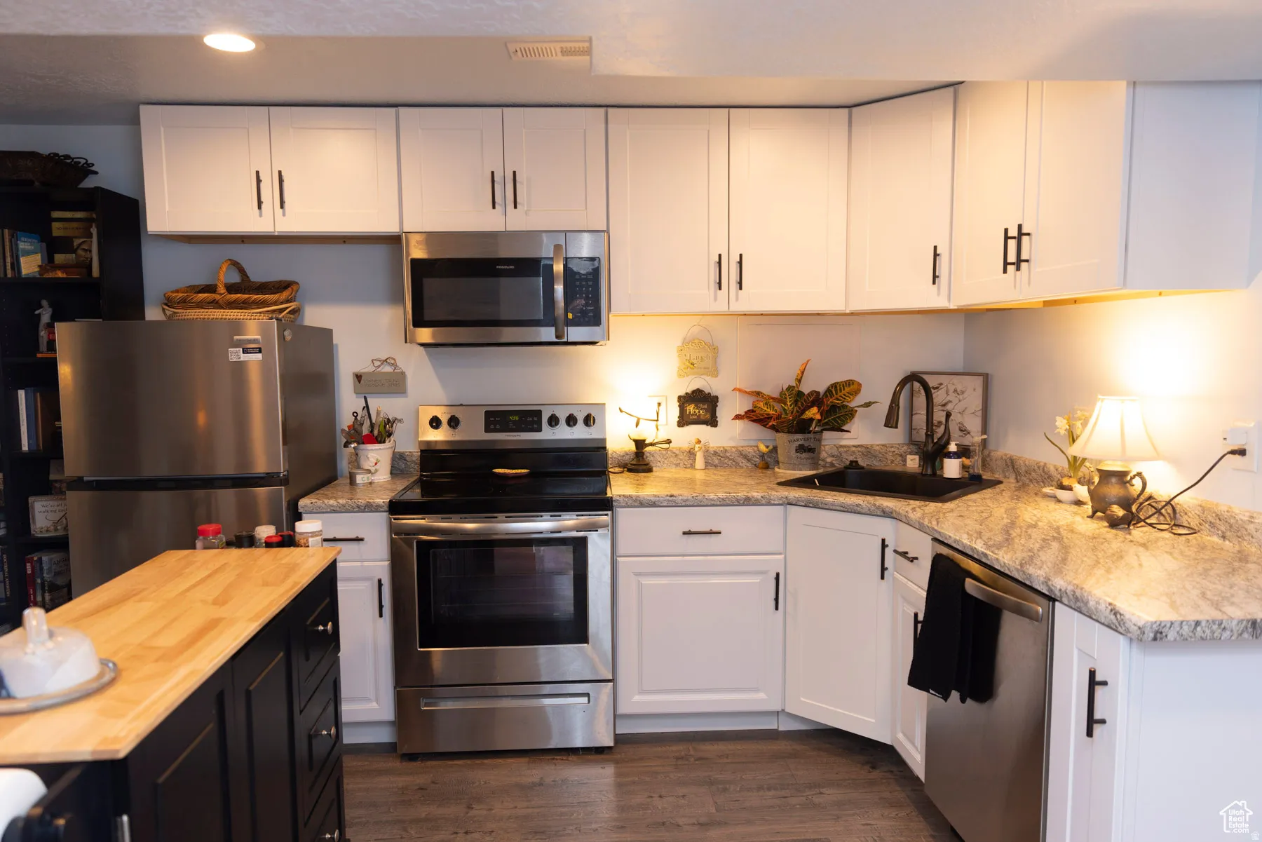 Kitchen with stainless steel appliances, wooden counters, dark wood-style floors, recessed lighting, and dual tone cabinetry