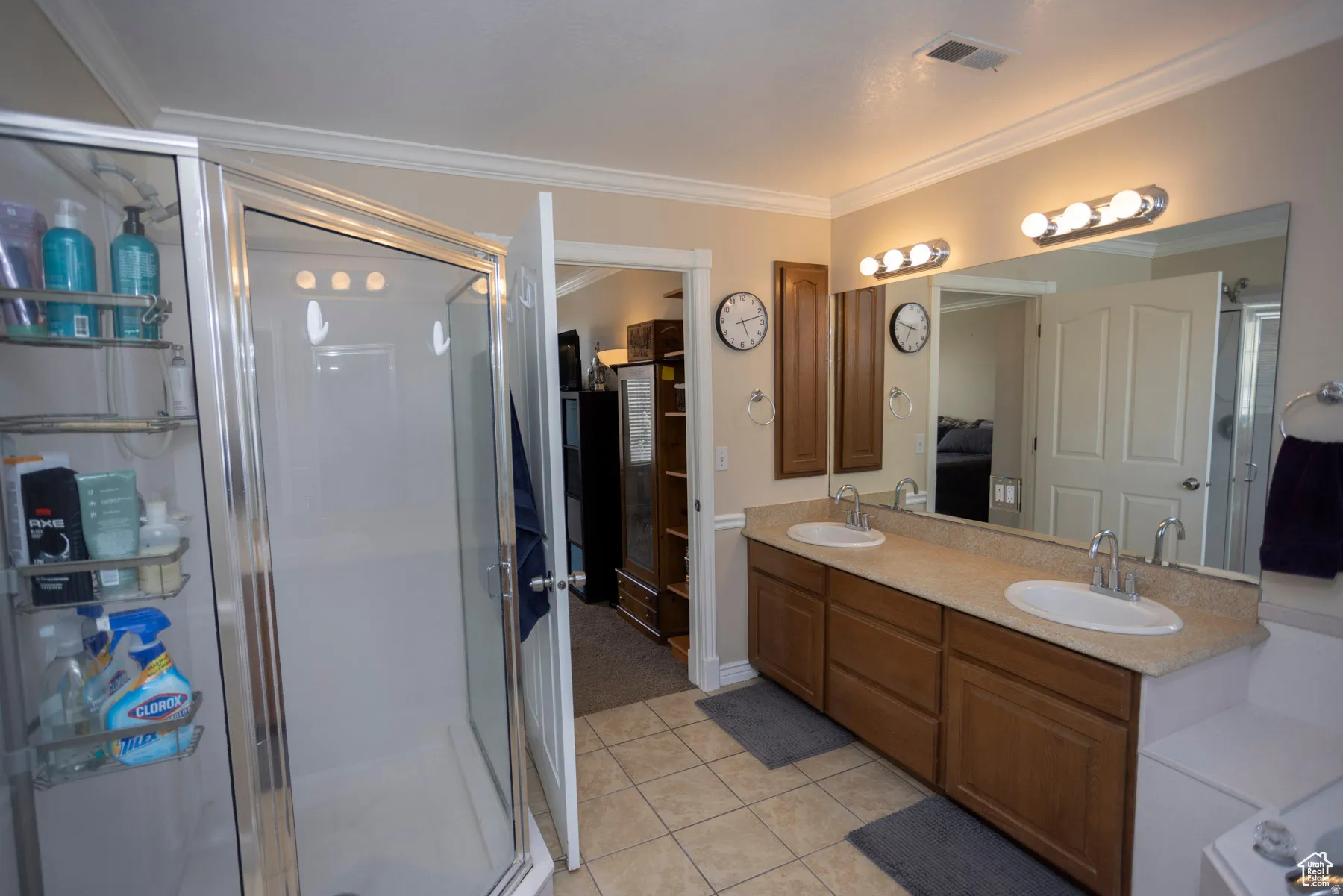 Primary Bedroom Ensuite bathroom with double vanity, crown molding, a stall shower, and light tile patterned floors