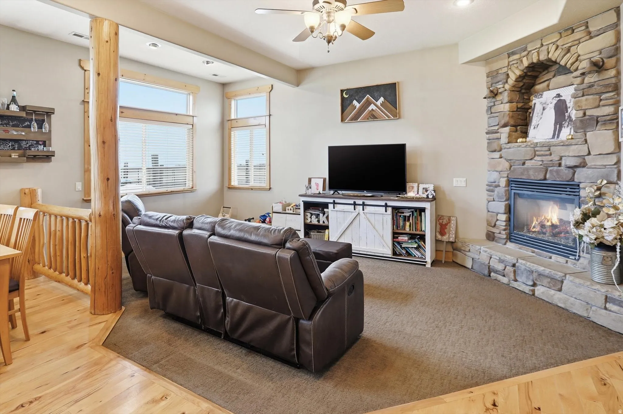 Living room featuring ceiling fan, a stone fireplace, wood finished floors, and recessed lighting