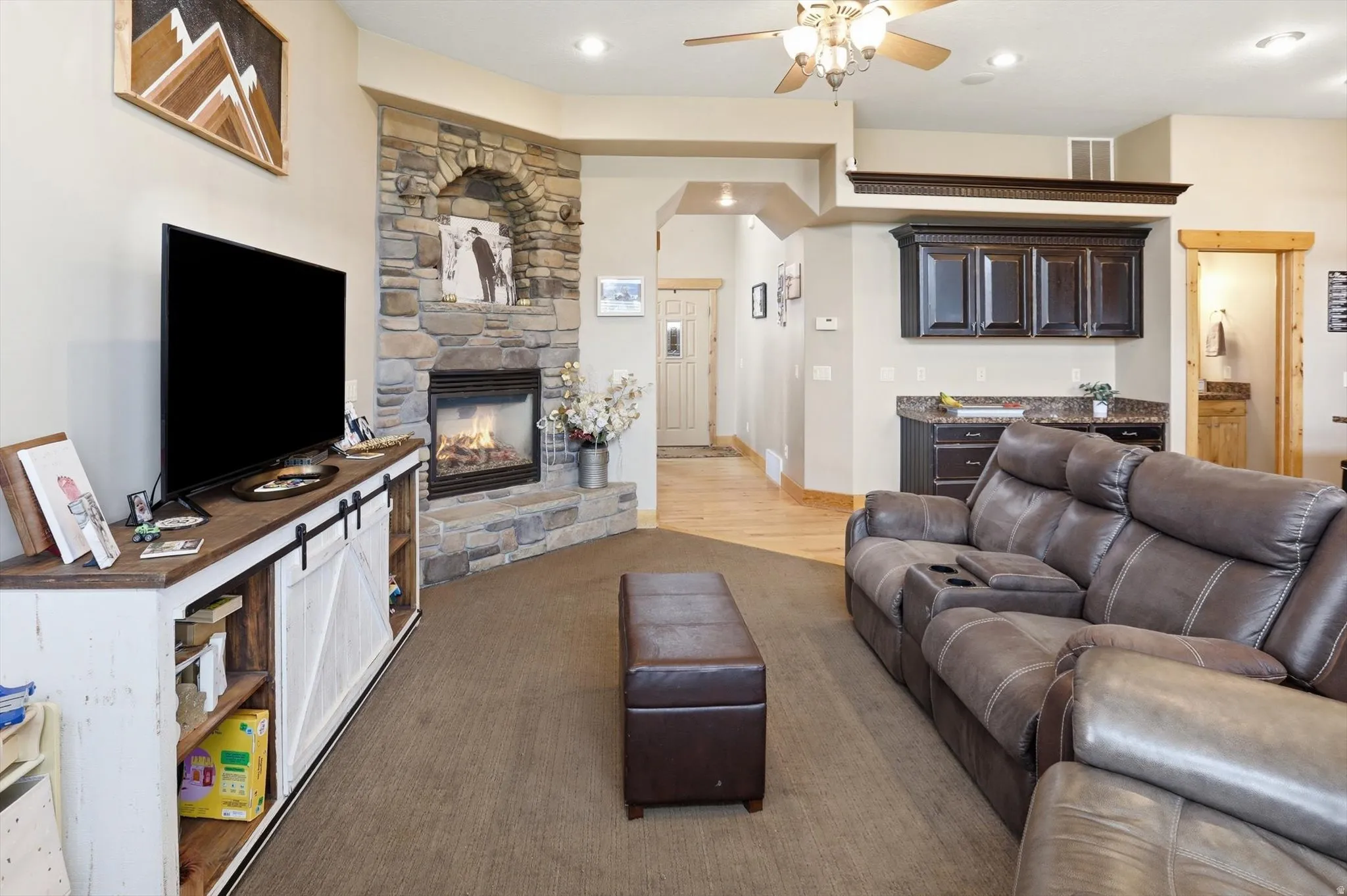 Living area with ceiling fan and a stone fireplace