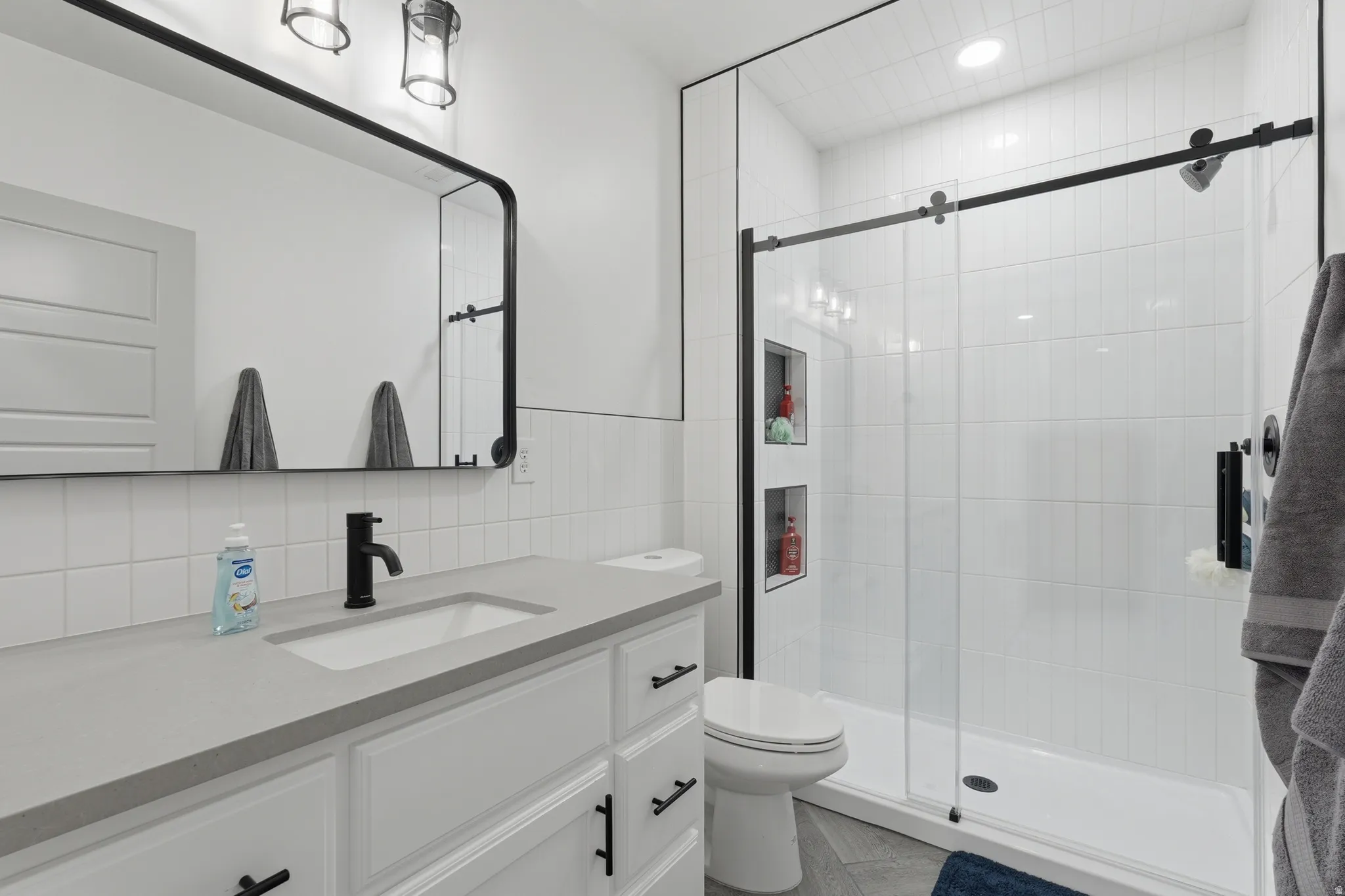 Bathroom featuring vanity, tile walls, a stall shower, and recessed lighting