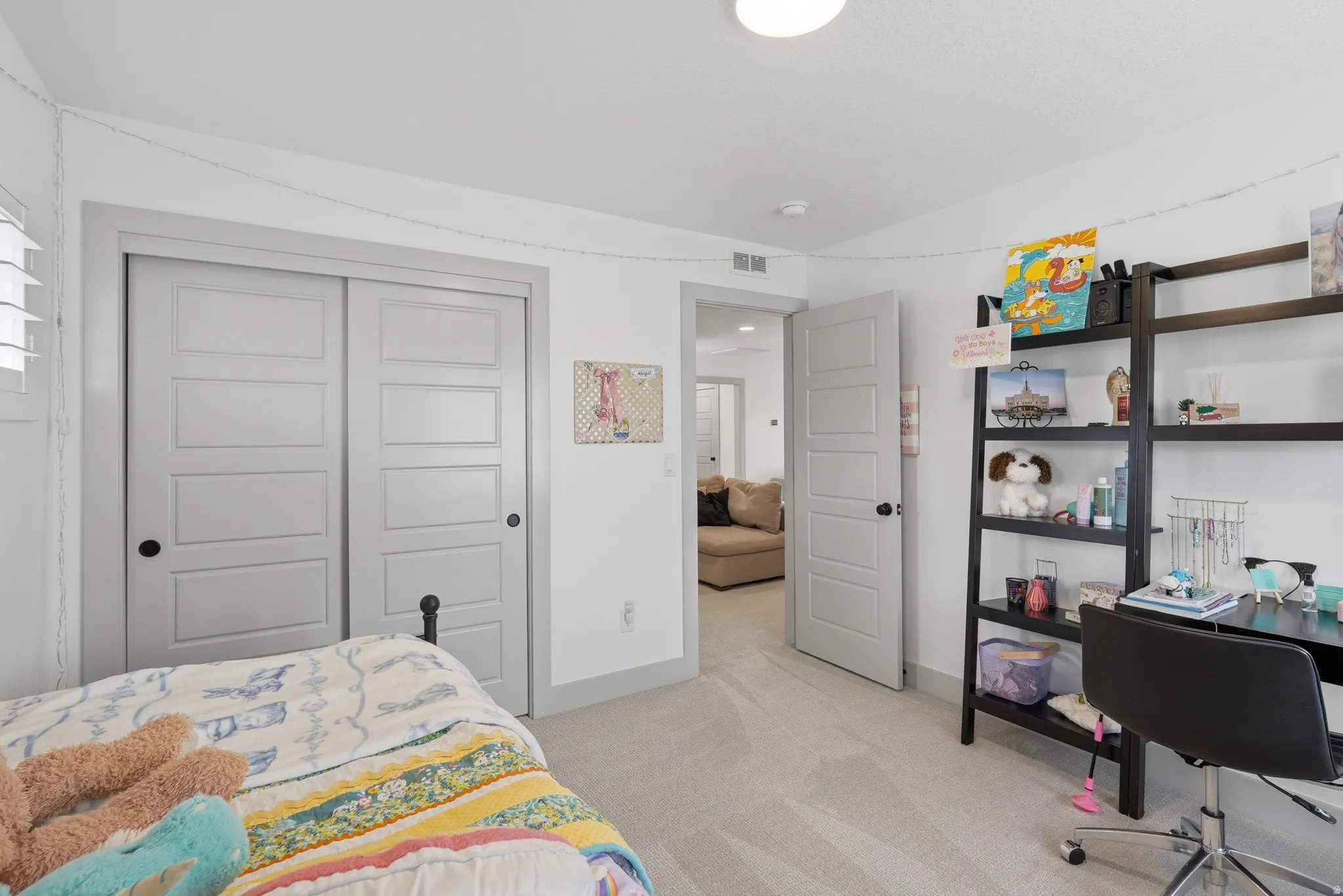 Bedroom with a closet, an office area, and light colored carpet