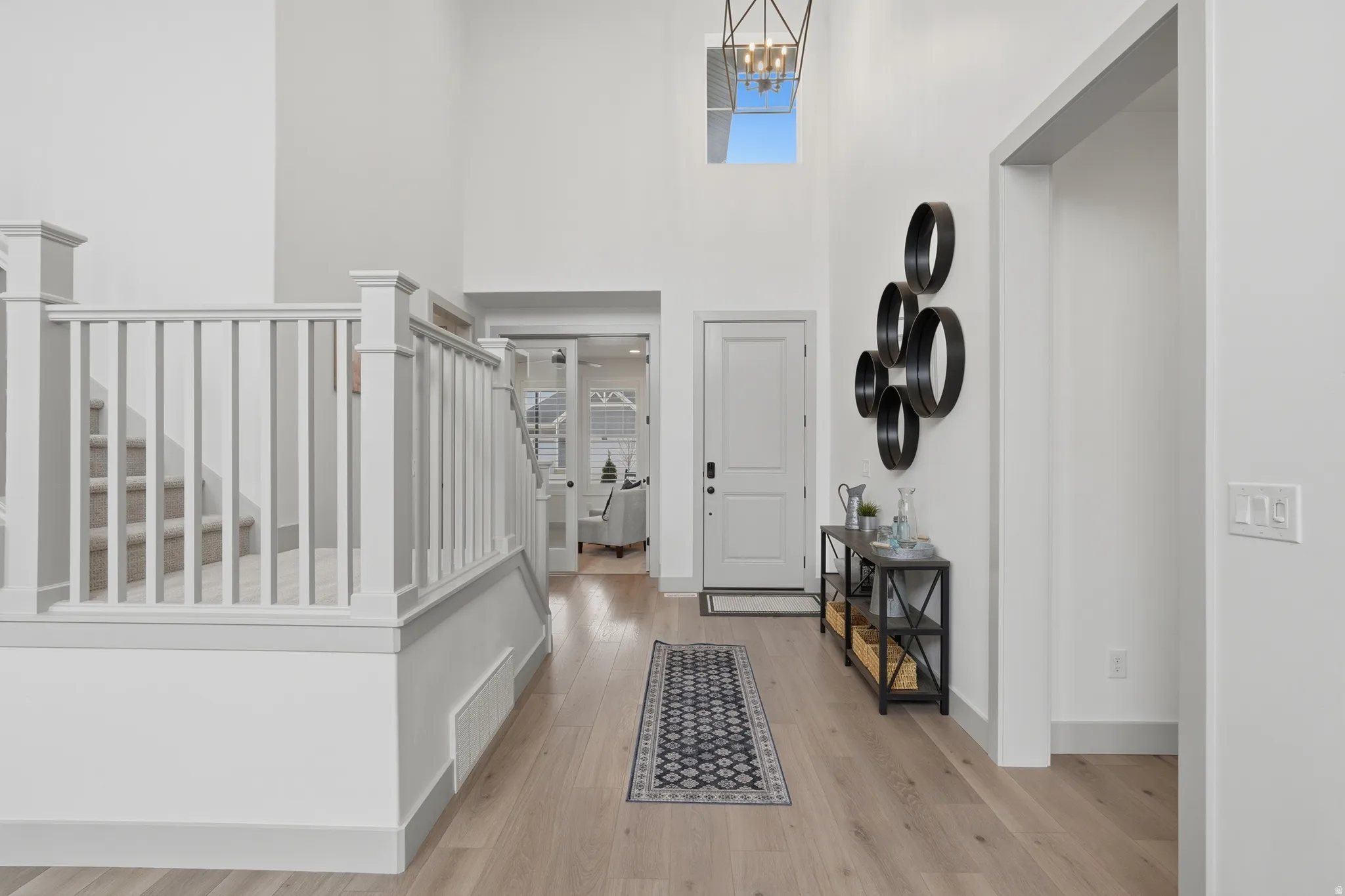 Foyer entrance with a high ceiling, light wood-style flooring, and a chandelier