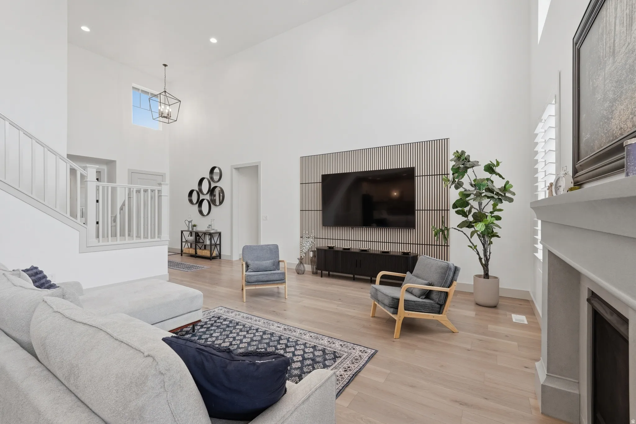 Living room with light wood finished floors, a high ceiling, a fireplace, and recessed lighting