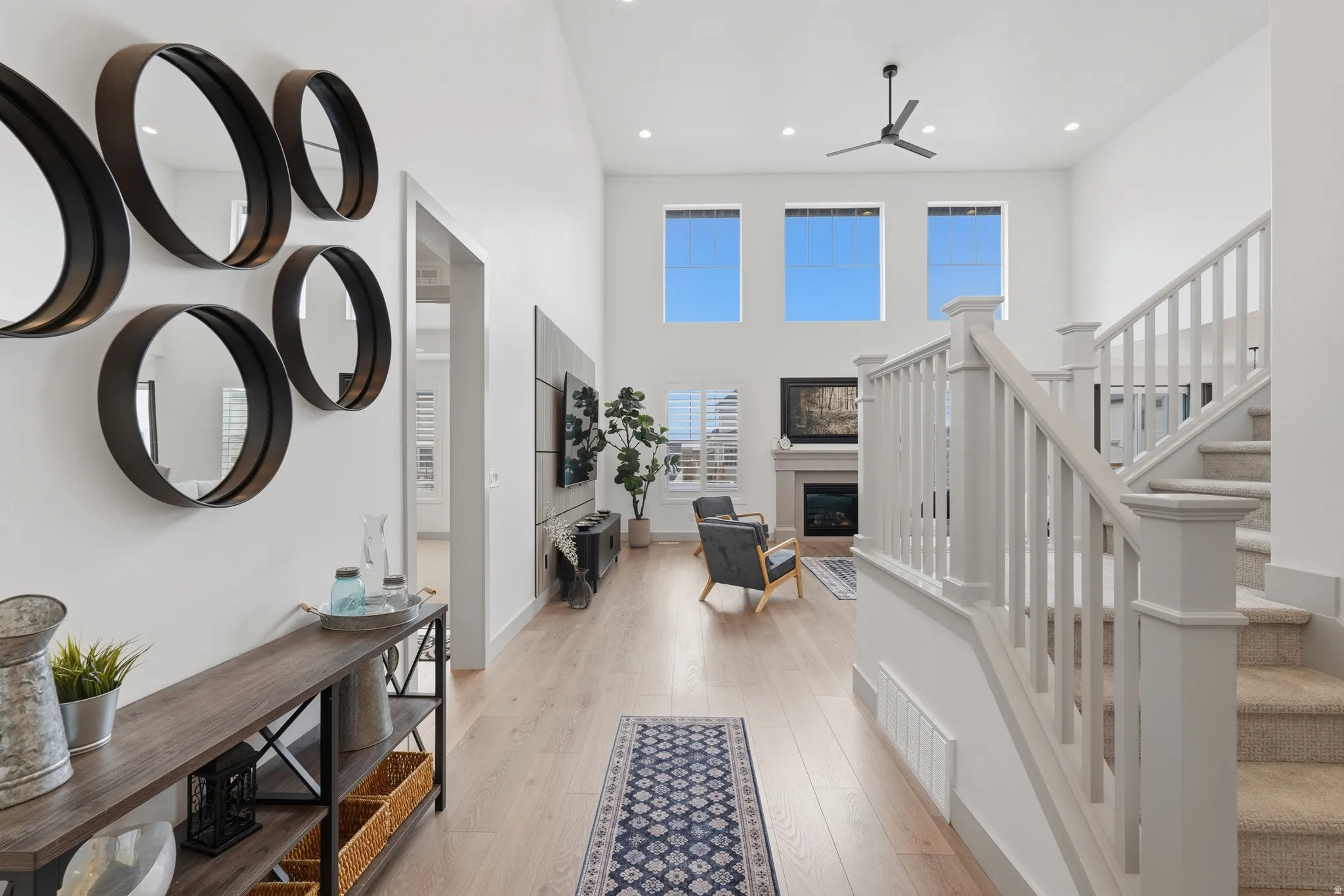 Foyer featuring a high ceiling, light wood-style floors, a glass covered fireplace, recessed lighting, and a ceiling fan