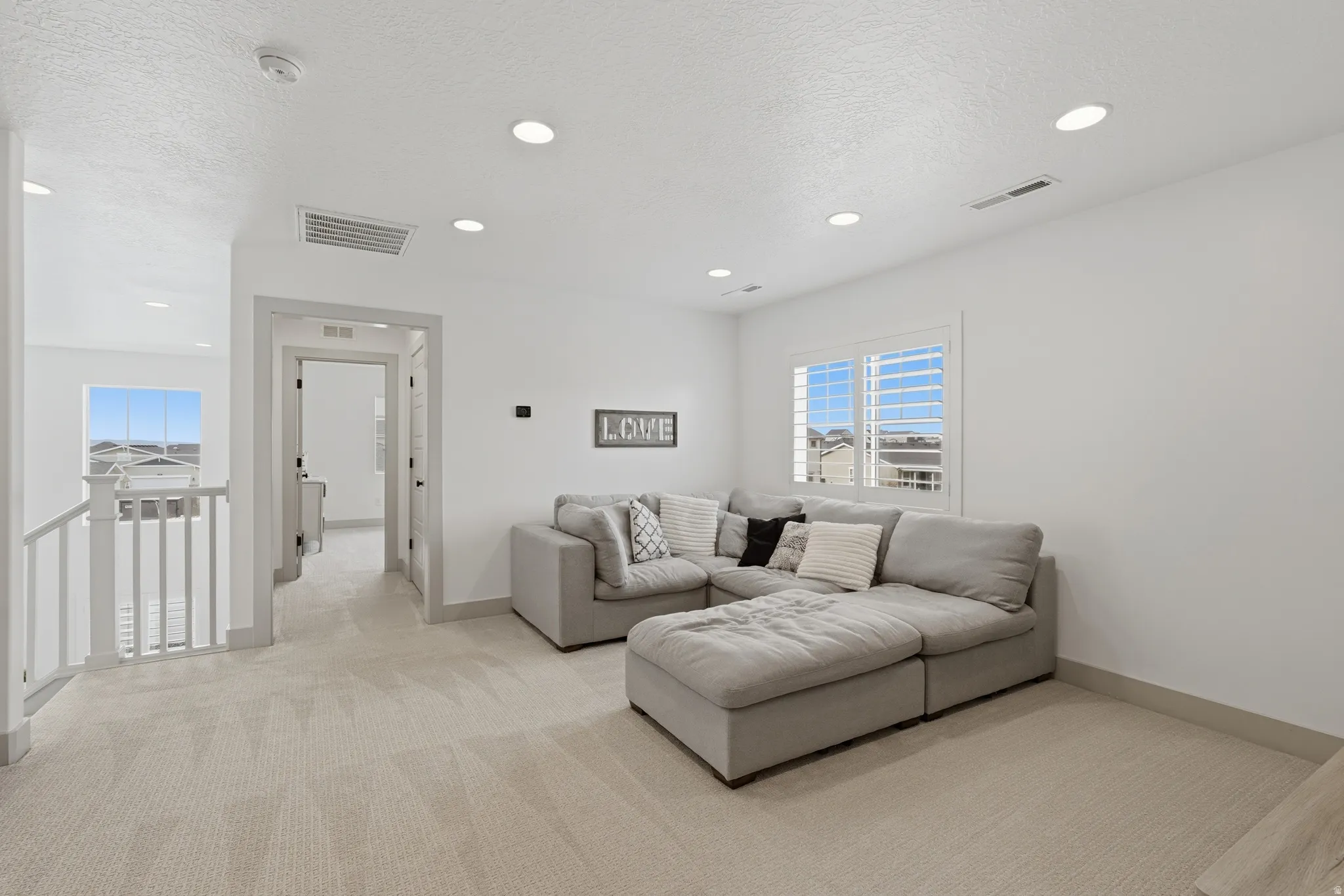 Living area featuring light colored carpet, a textured ceiling, and recessed lighting