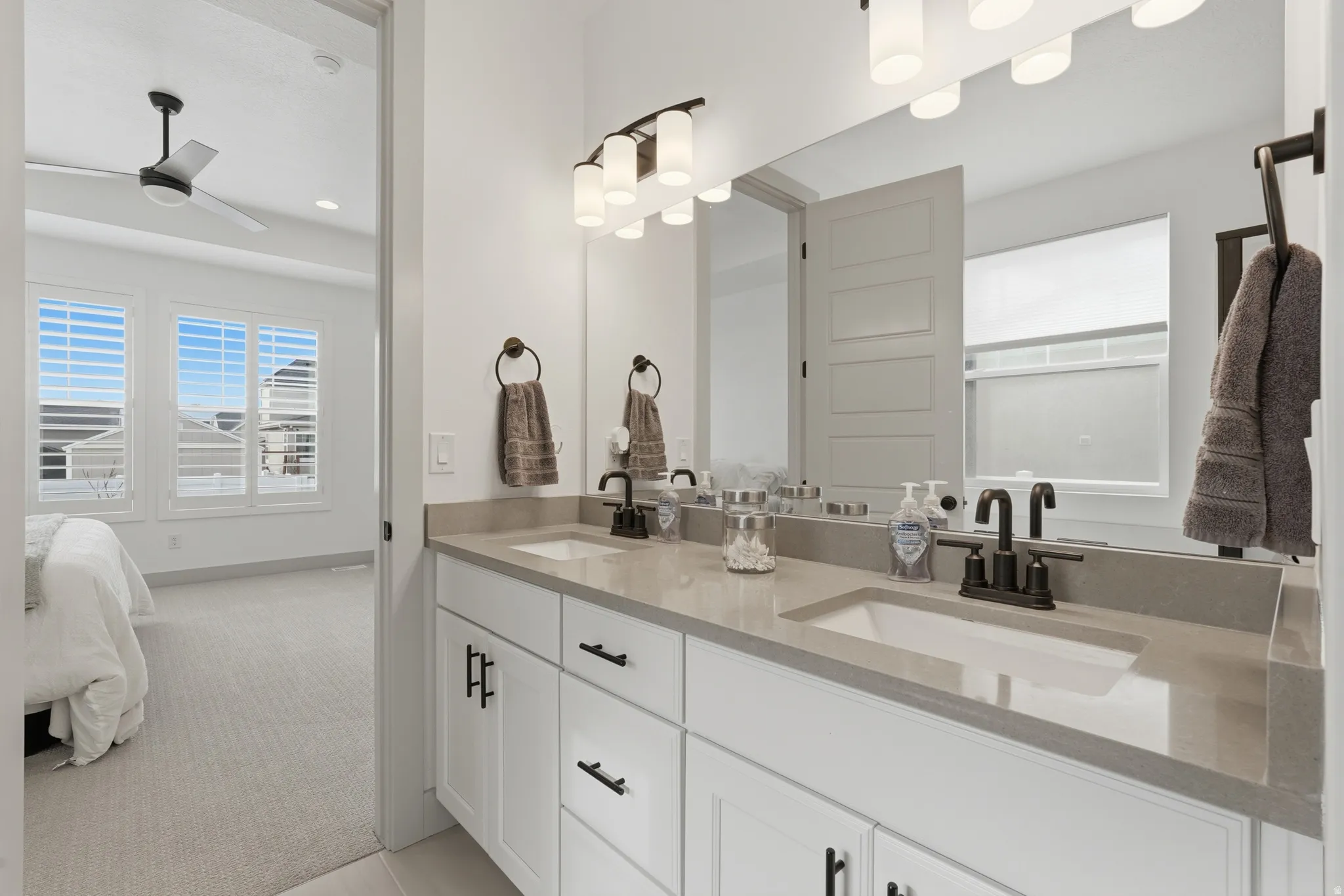Full bathroom featuring double vanity, light colored carpet, a ceiling fan, and ensuite bathroom