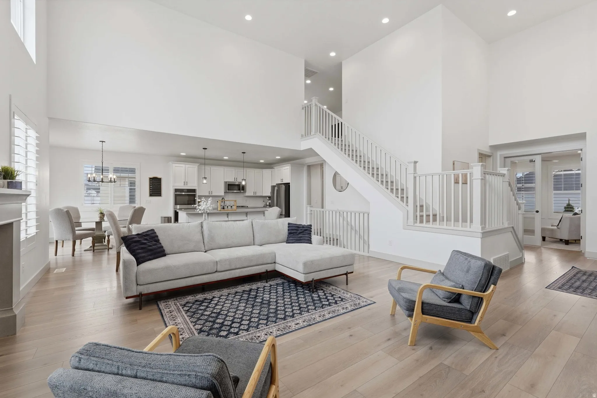 Living room with light wood-style flooring, a high ceiling, and a chandelier