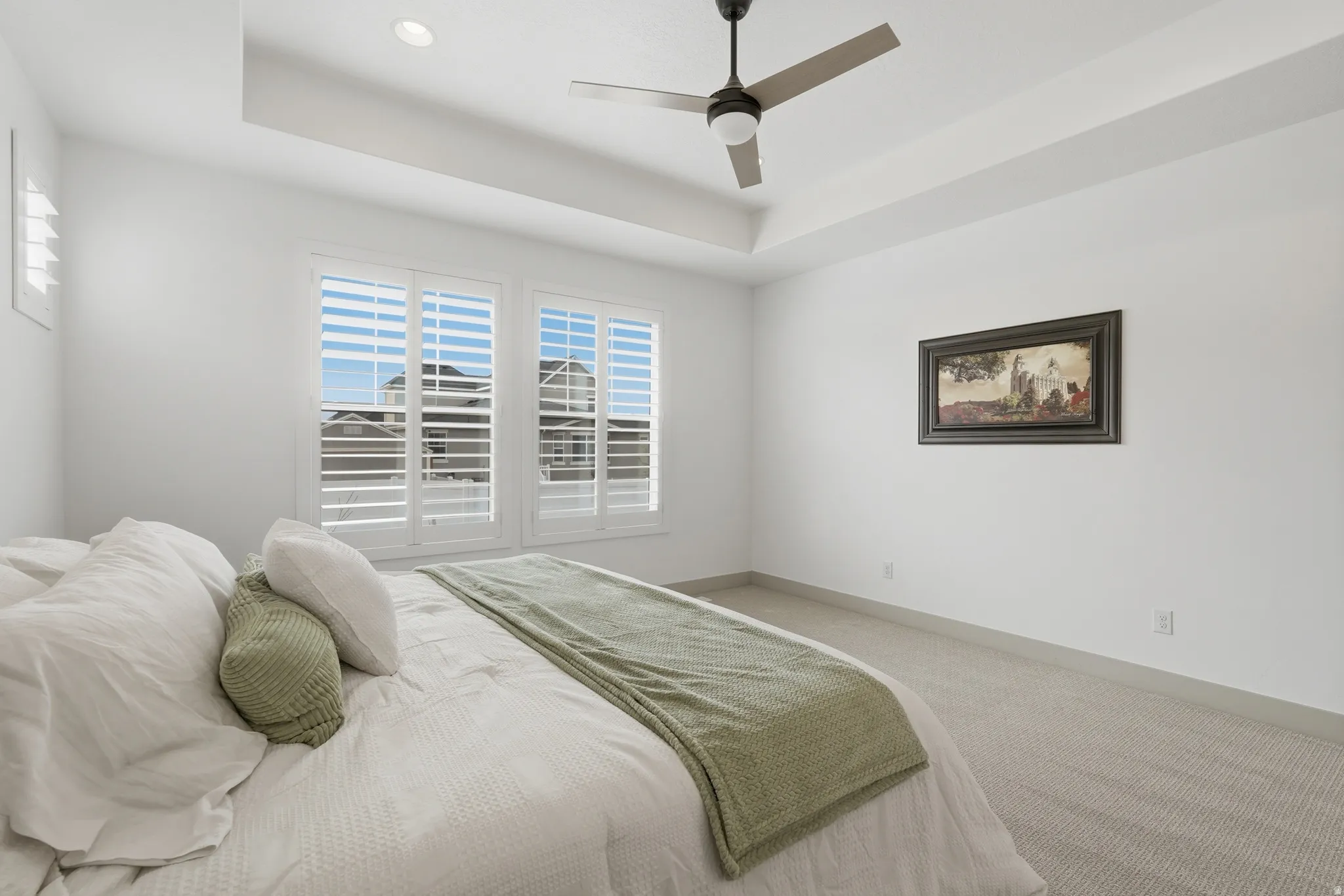 Carpeted bedroom featuring ceiling fan and a tray ceiling