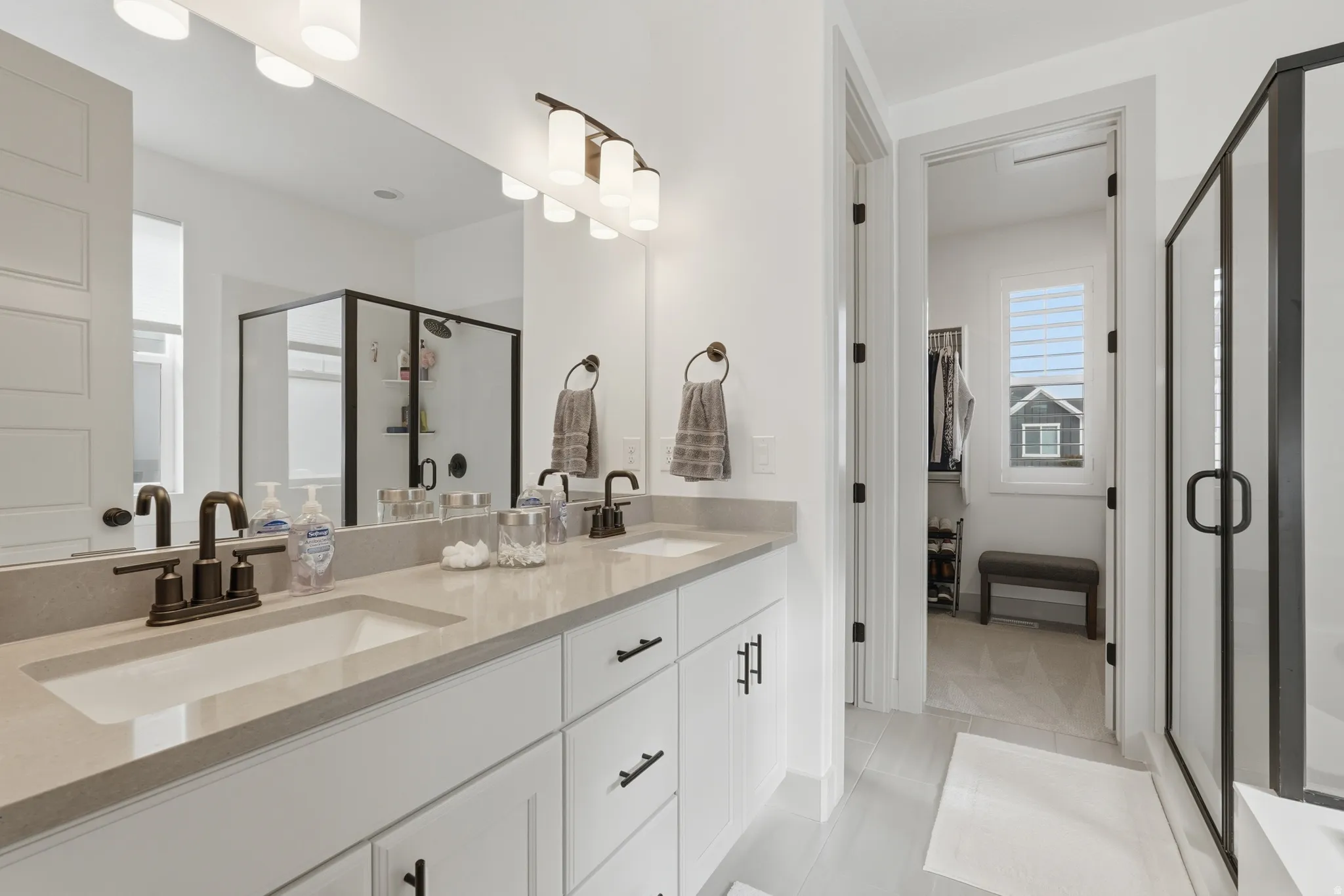 Bathroom with a stall shower, double vanity, and light tile patterned floors