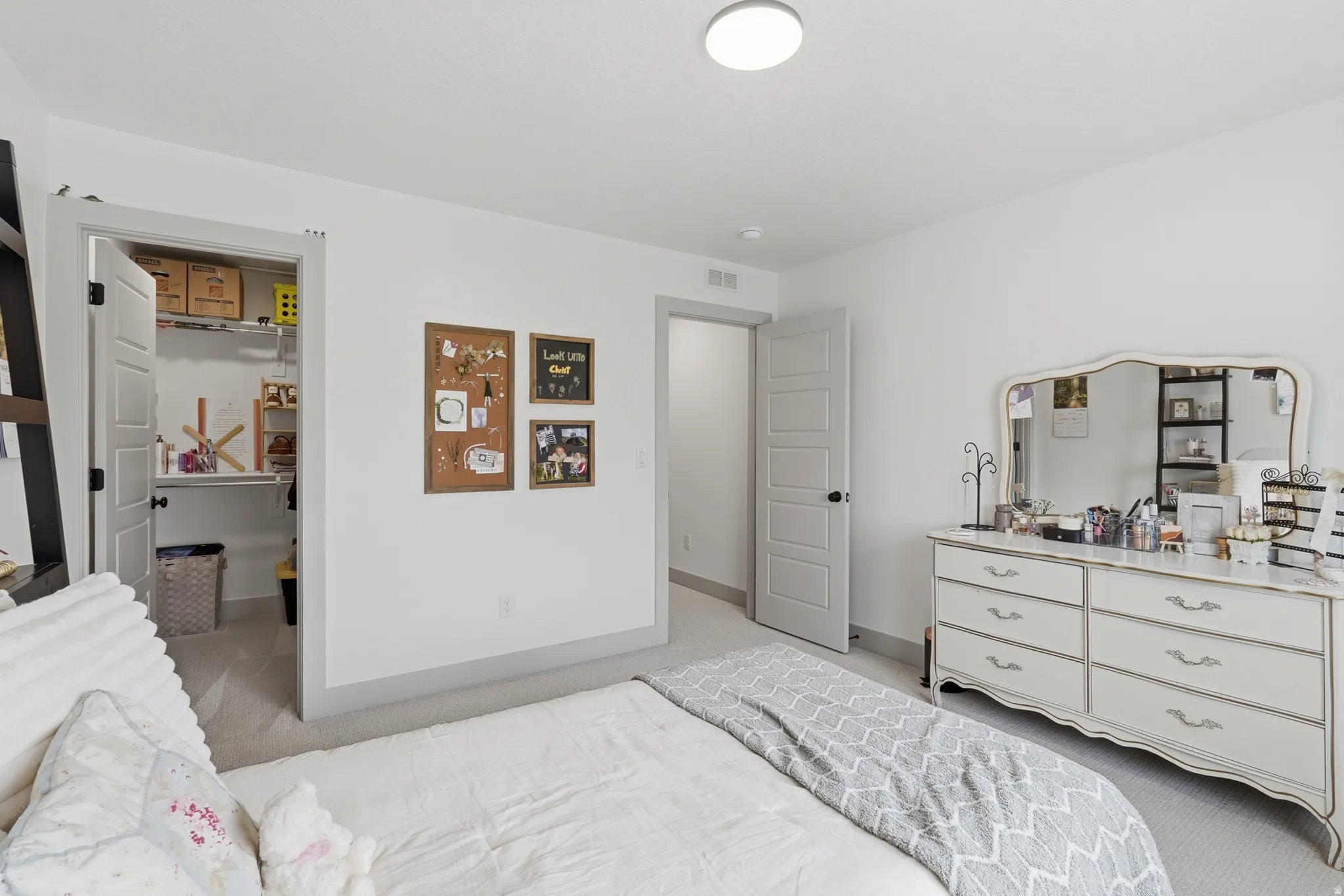 Bedroom with light colored carpet and a walk in closet