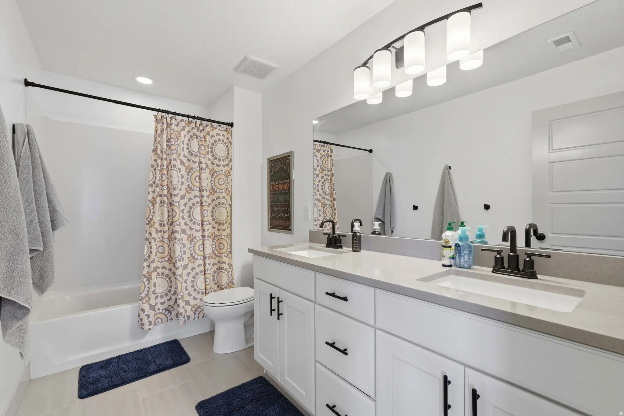Bathroom featuring double vanity and shower / tub combo with curtain