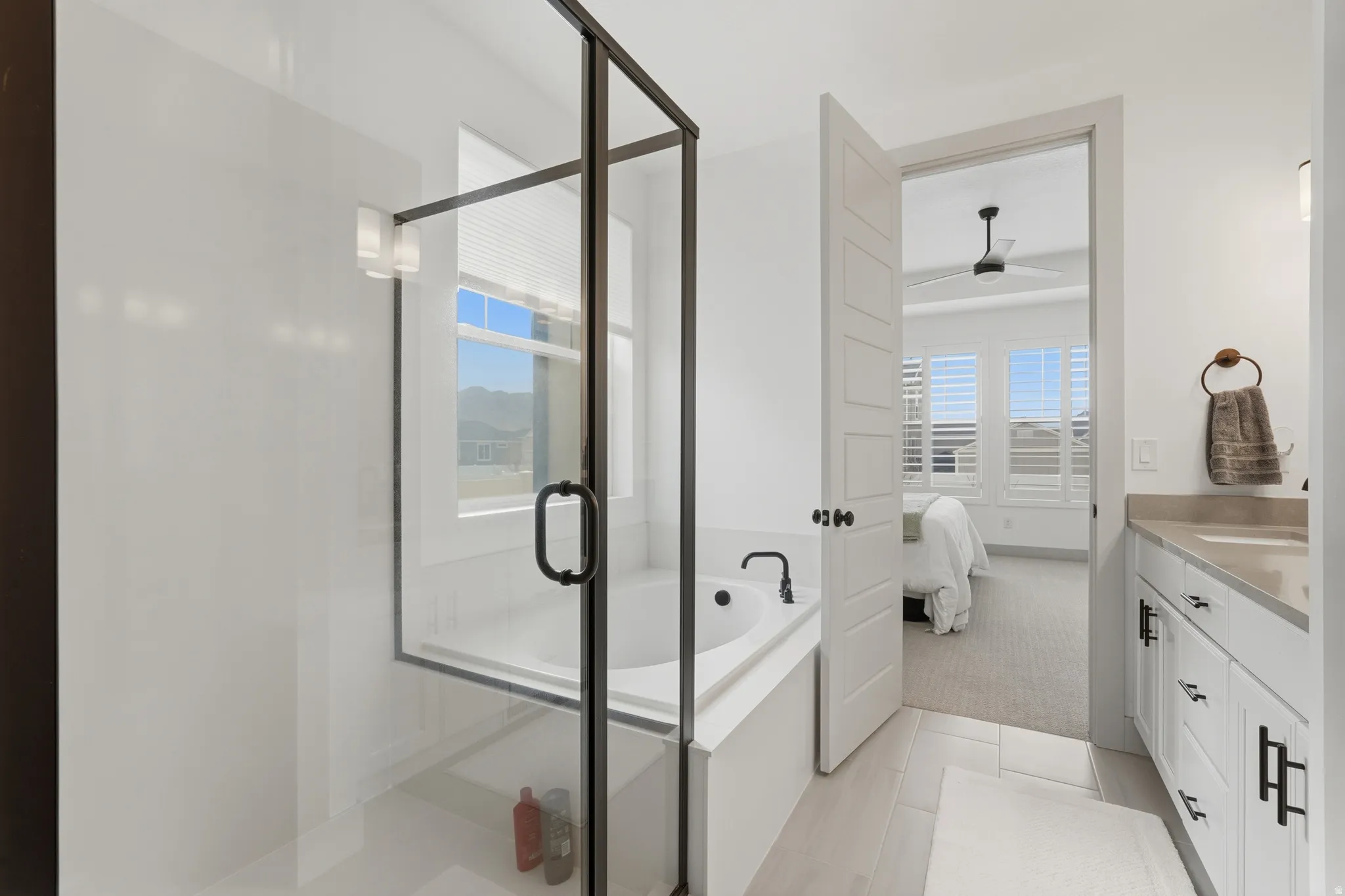 Full bath featuring connected bathroom, vanity, a shower stall, a garden tub, and light carpet