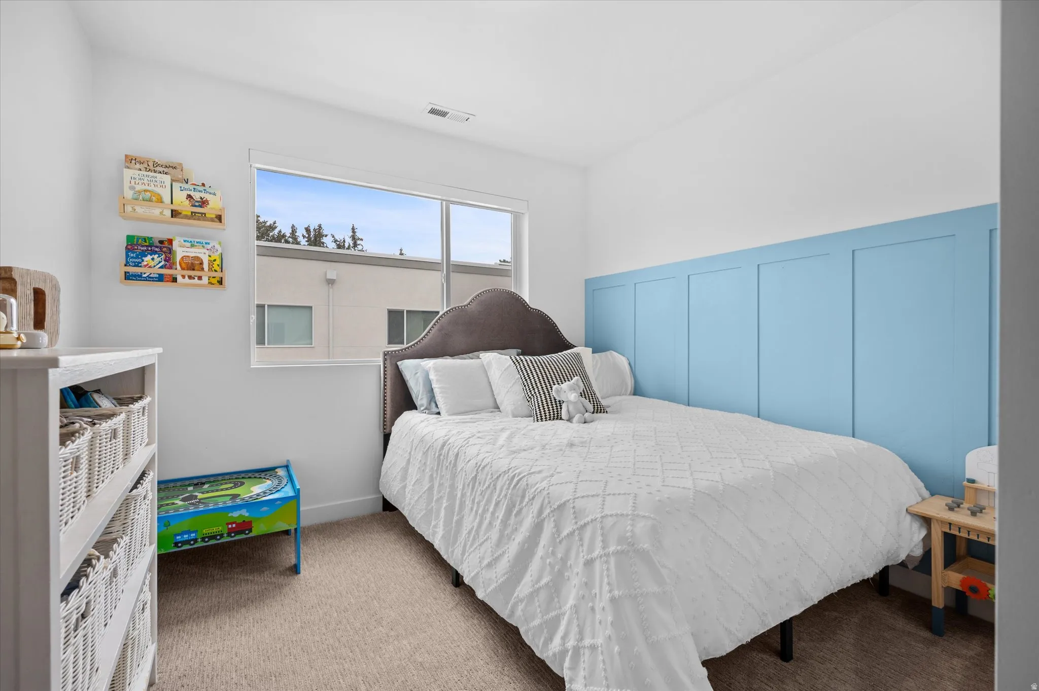 Bedroom with decorative wainscoting, large window for natural light, and walk in closet.