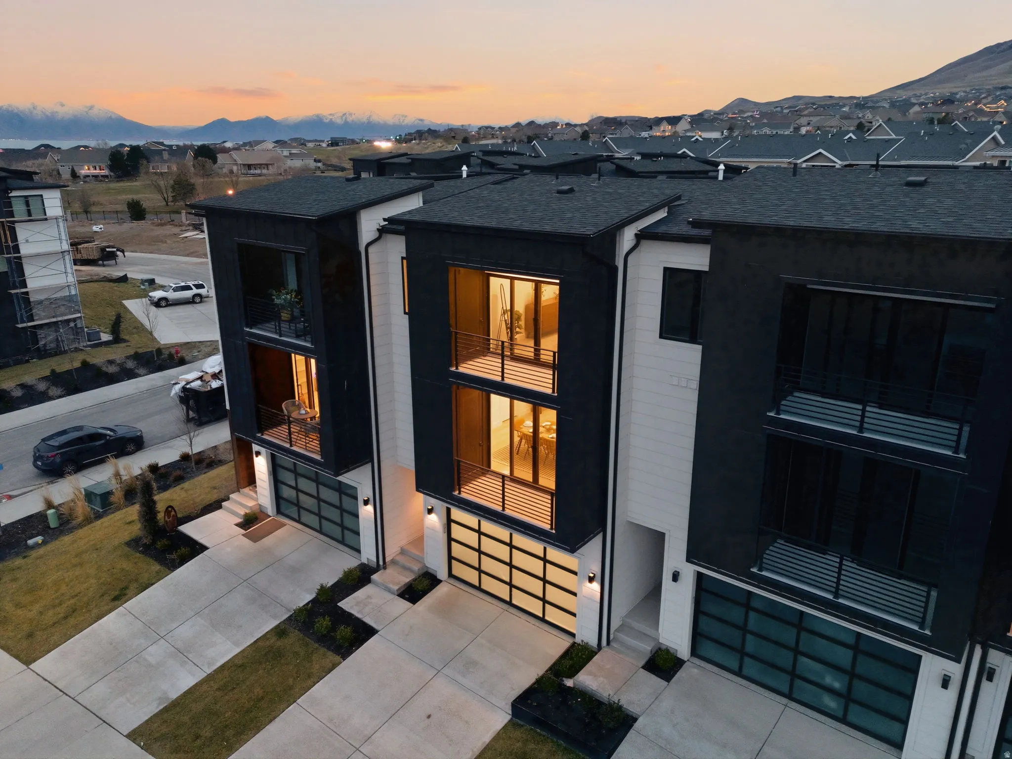 Exterior entry at dusk featuring an attached garage, concrete driveway, and roof with shingles