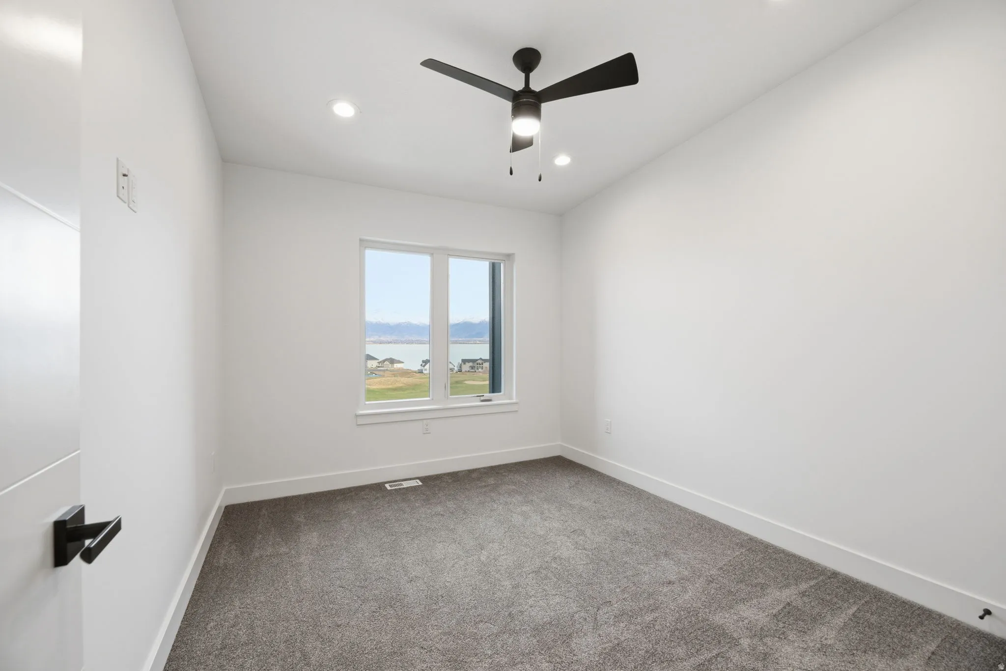 Unfurnished room with dark colored carpet, a ceiling fan, a water view, and recessed lighting