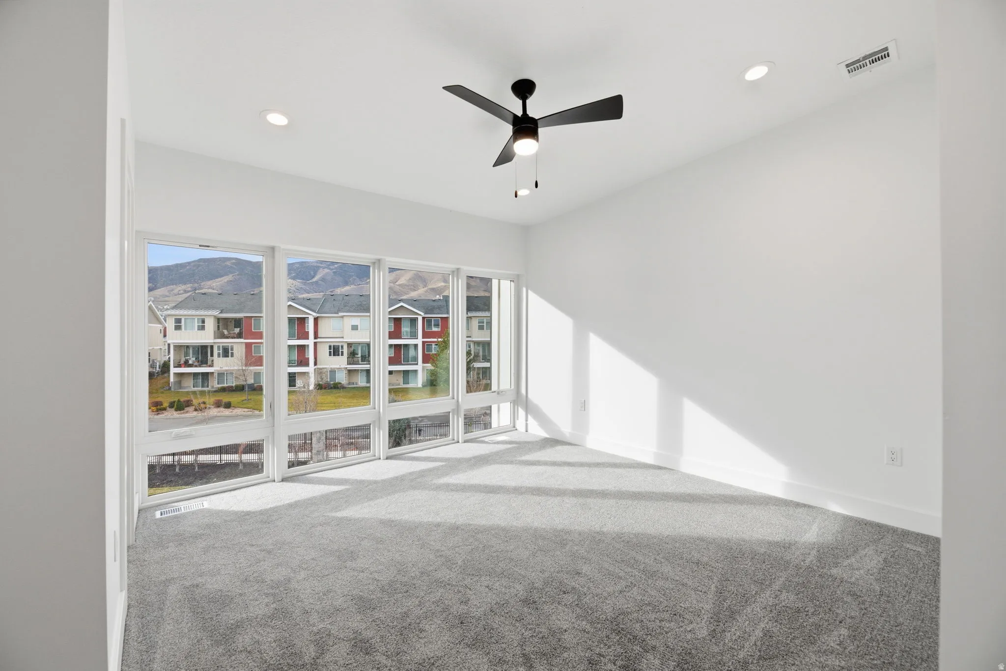 Empty room featuring light carpet, ceiling fan, recessed lighting, and a mountain view