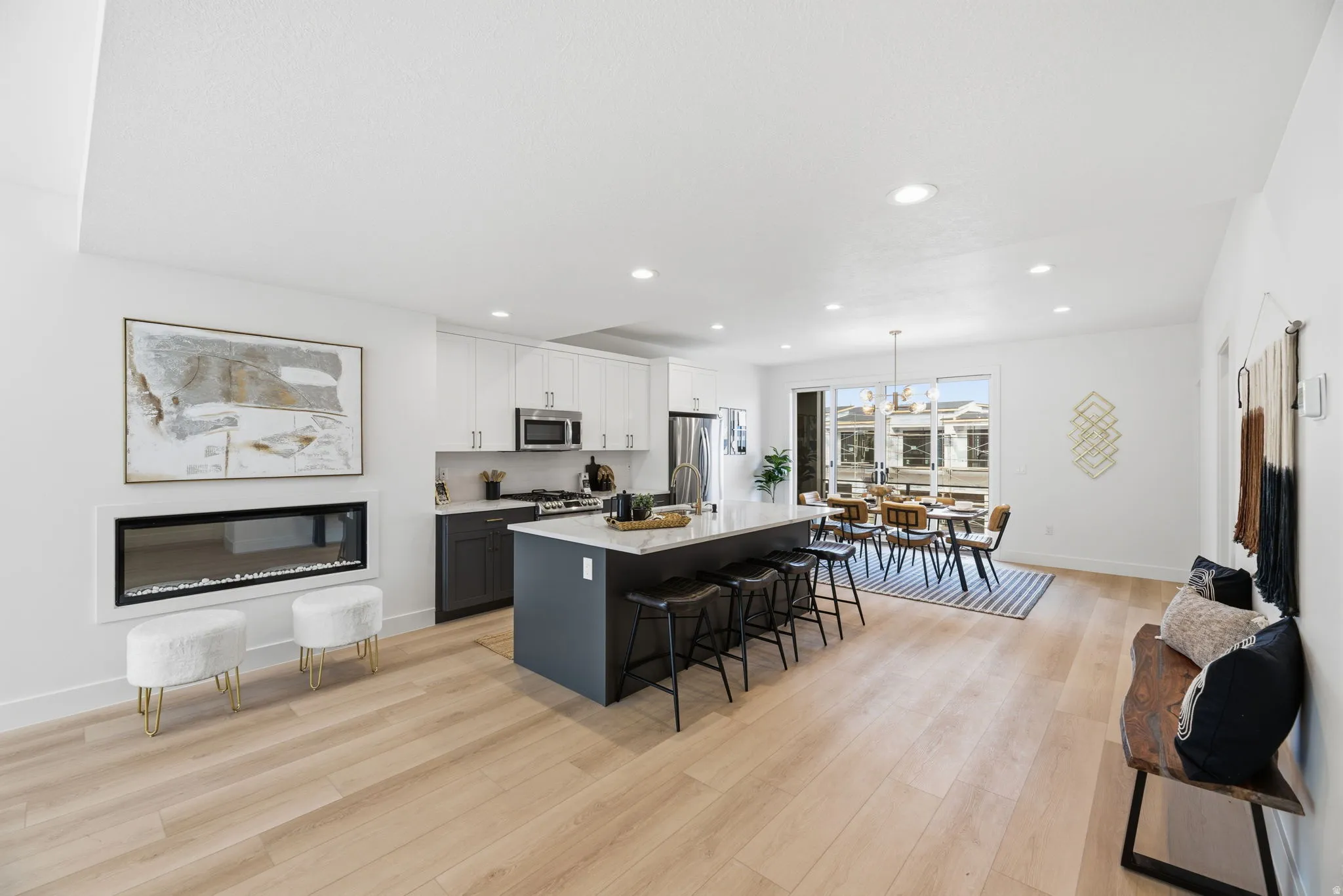 Kitchen featuring dual tone cabinets, a breakfast bar area, a center island with sink, light wood-style floors, and stainless steel appliances