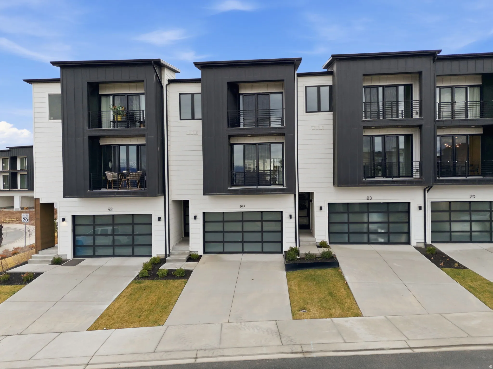 Modern home with board and batten siding, a garage, concrete driveway, and a balcony
