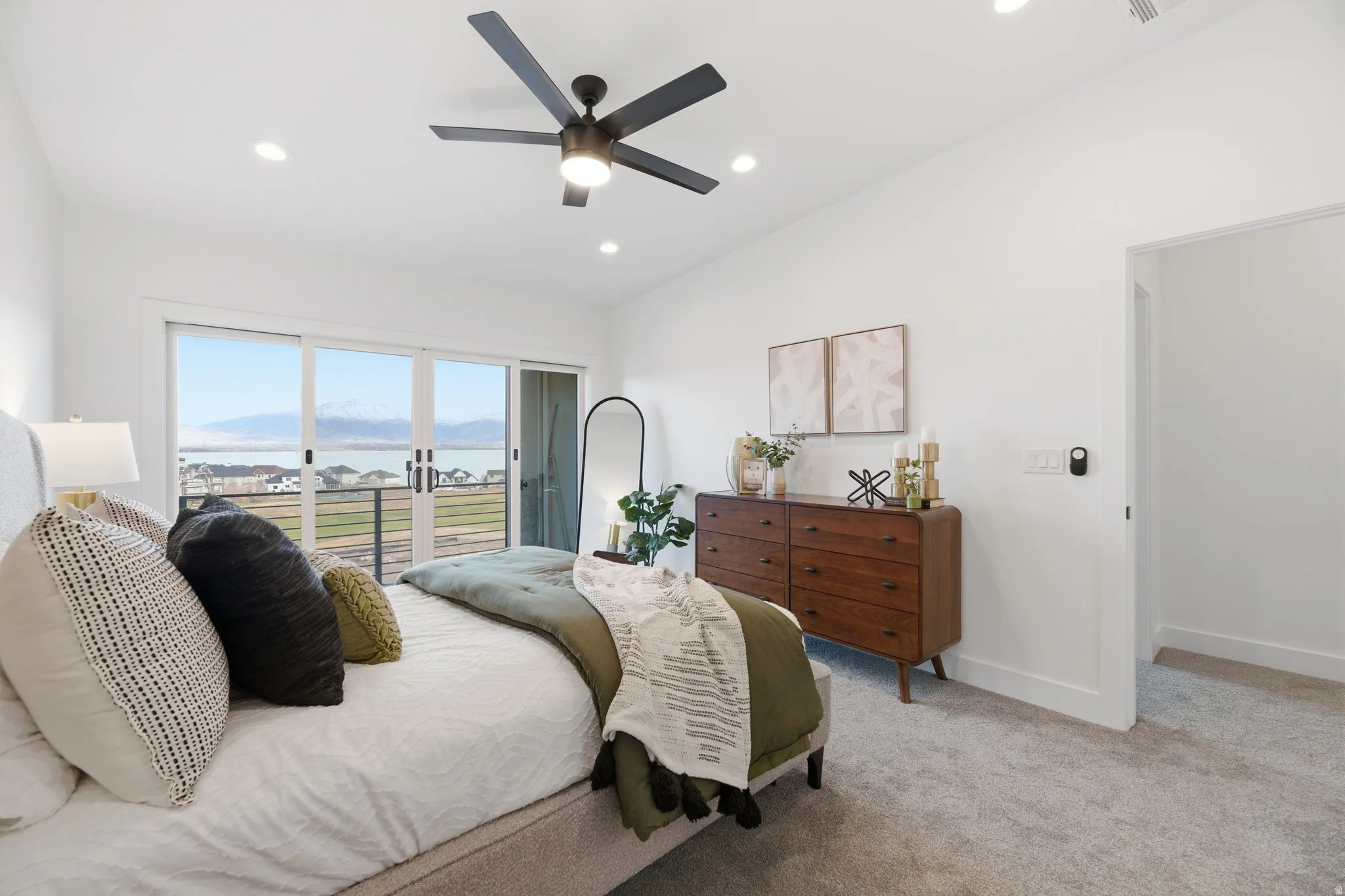 Bedroom with vaulted ceiling, access to outside, a water and mountain view, light carpet, and a ceiling fan
