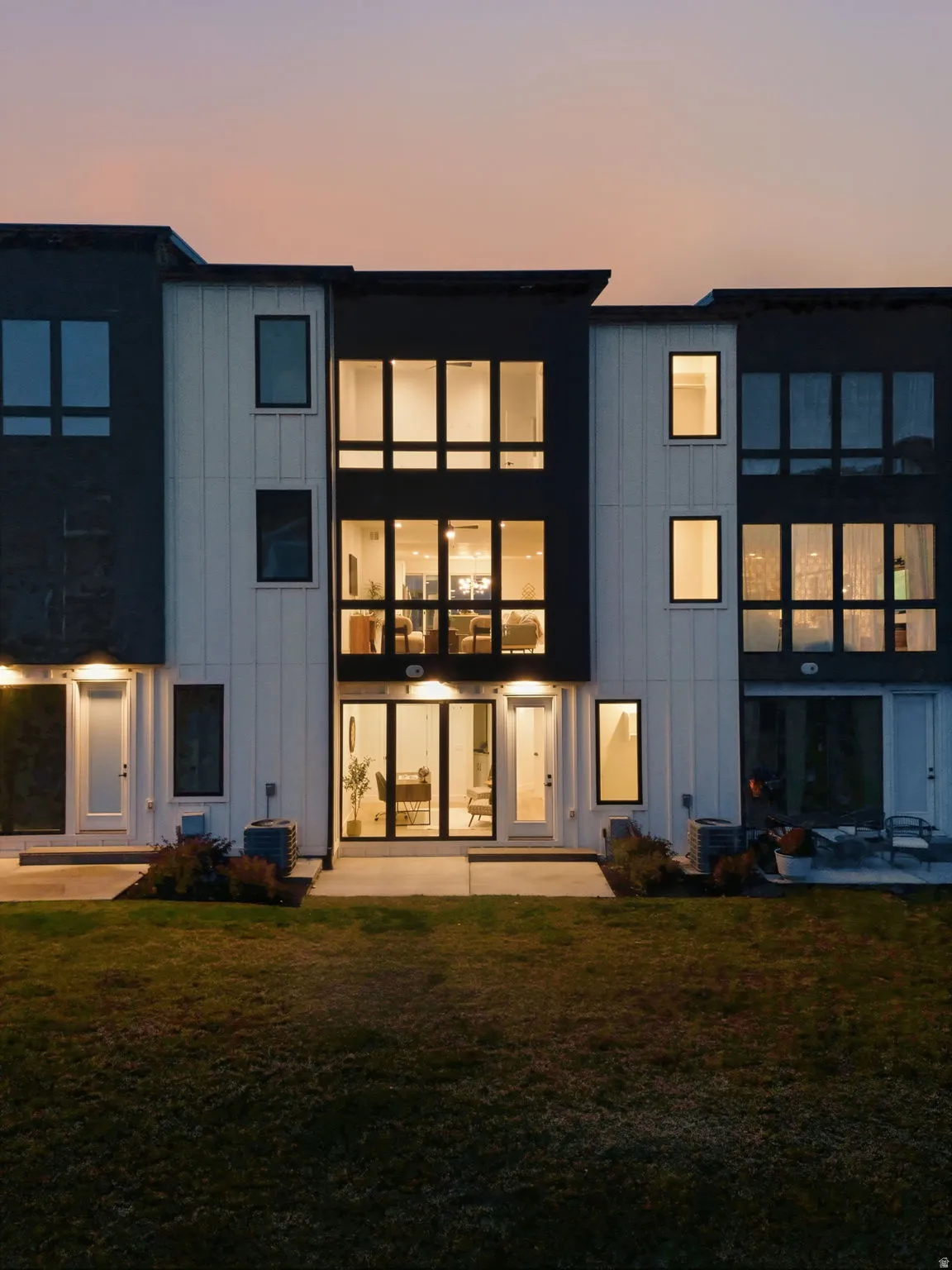 Back of property at dusk featuring a lawn, board and batten siding, and a patio area
