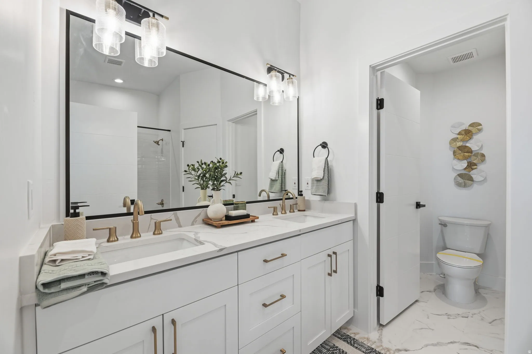 Bathroom with double vanity, light marble finish flooring, and a shower stall