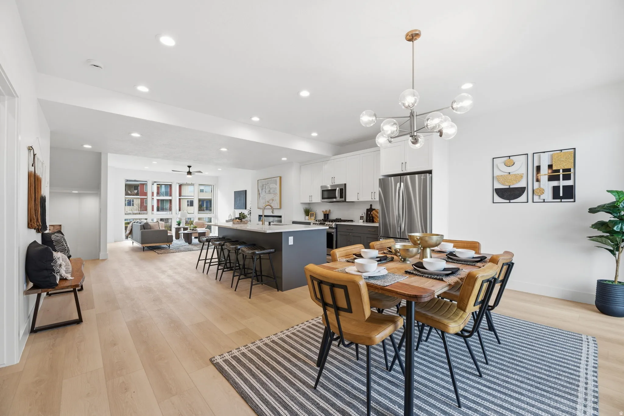 Dining room with light wood-style flooring, ceiling fan, and hanging lights
