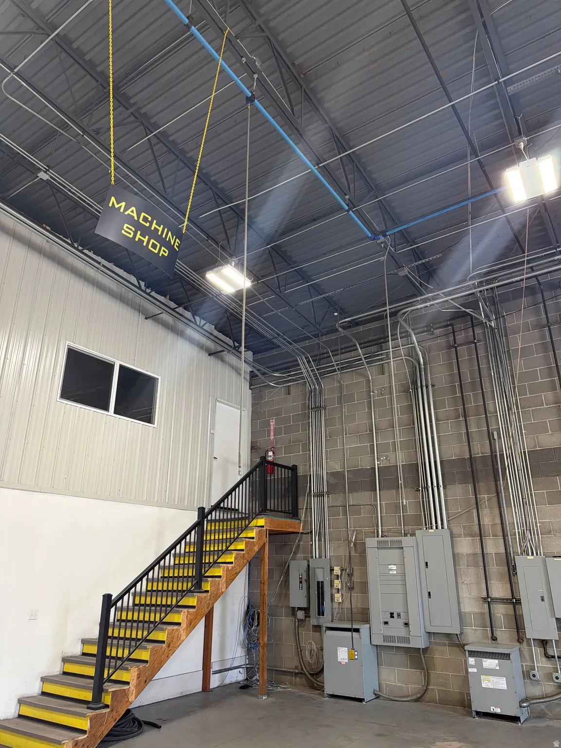 Garage with electric panel, metal wall, and concrete block wall