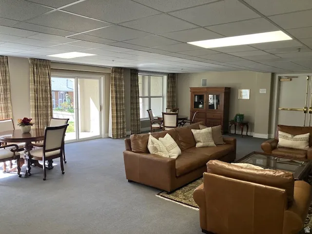 Living area with carpet floors, healthy amount of natural light, and a paneled ceiling