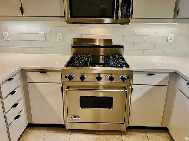 Kitchen with Viking Gas Range , light stone counters, and decorative backsplash