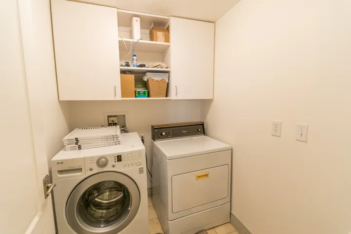 Laundry area featuring washer and dryer, cabinet space, and light tile patterned floors