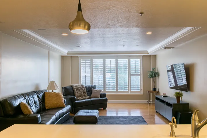 Living area featuring a raised ceiling, a textured ceiling, light wood-style flooring, crown molding, and recessed lighting