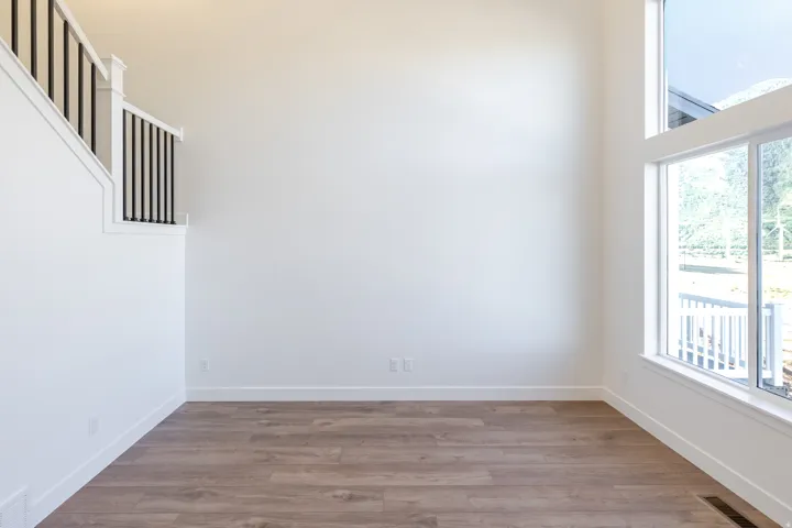 Expansive double-height room featuring large windows and wood-finish flooring