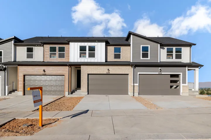 Contemporary townhome facade featuring mixed siding, a dark roofline, and attached garages