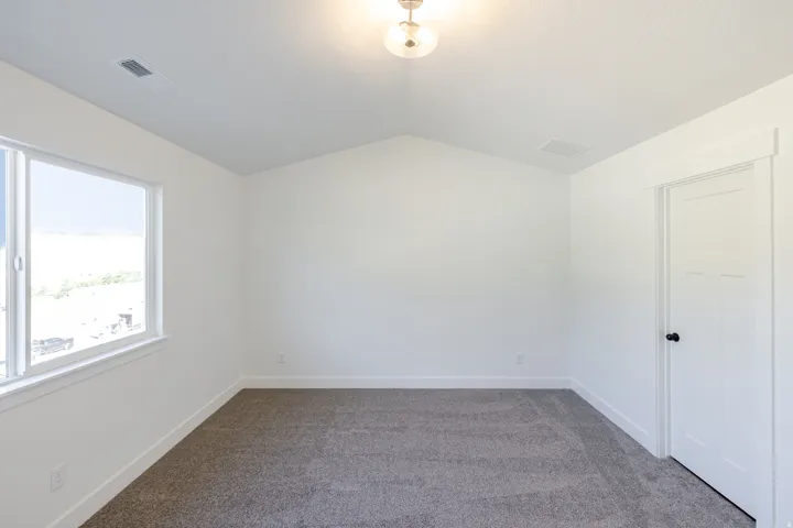 Carpeted room featuring a vaulted ceiling and a single-pane window