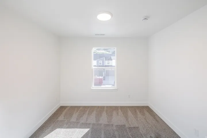 Room featuring neutral gray patterned carpet, white walls, and a single window with white trim