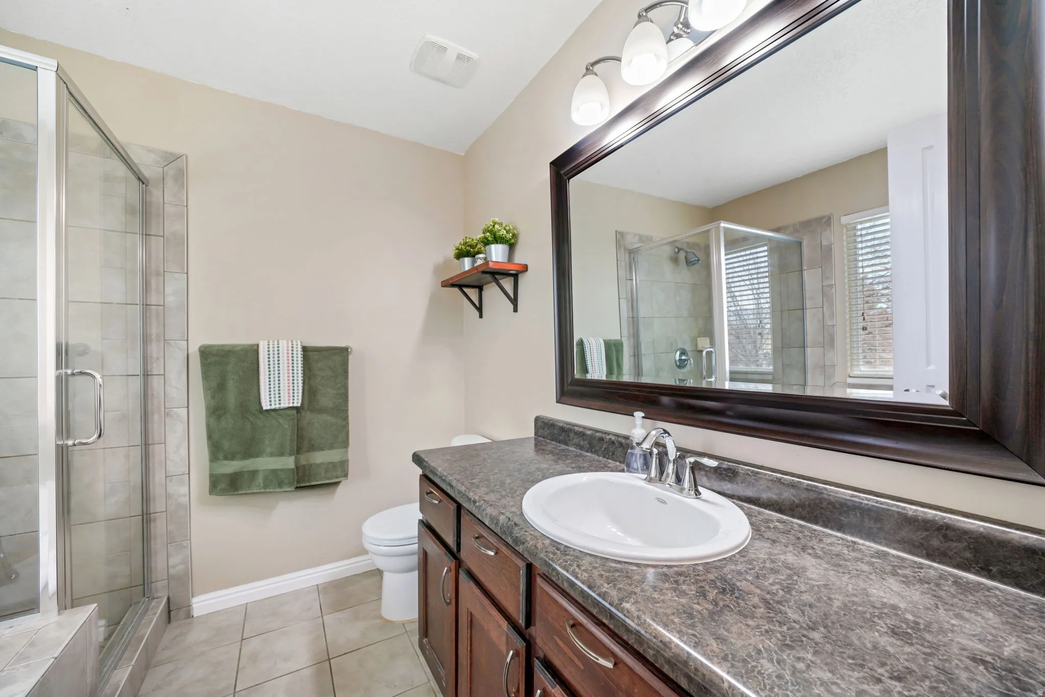 Bathroom featuring vanity, a shower stall, and light tile patterned floors