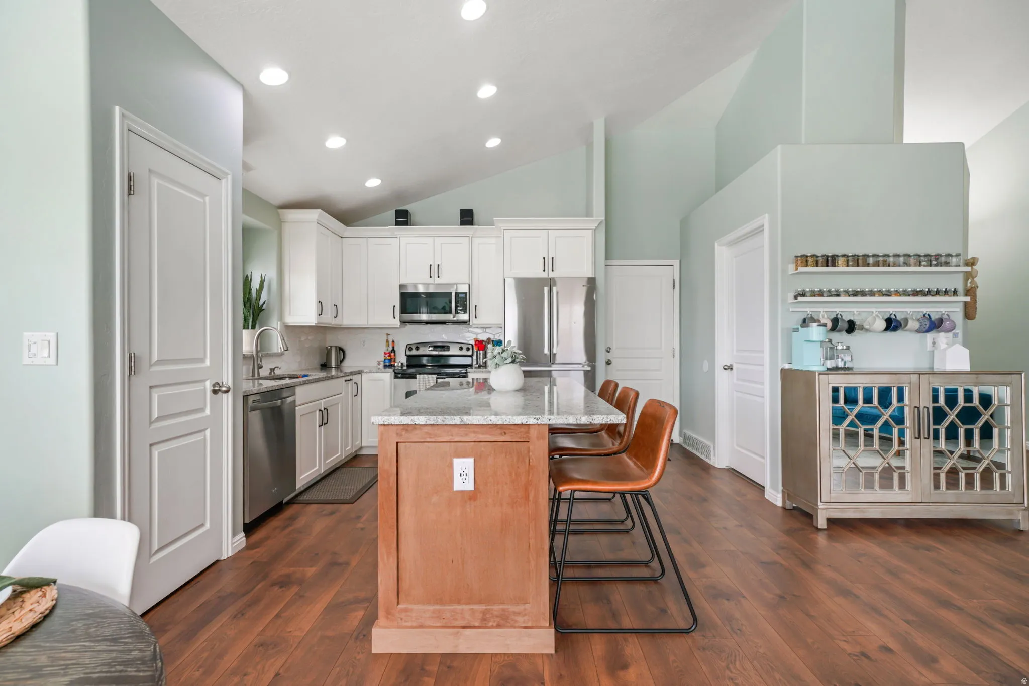 Kitchen featuring a center island, lofted ceiling, stainless steel appliances, two tone color scheme, and backsplash