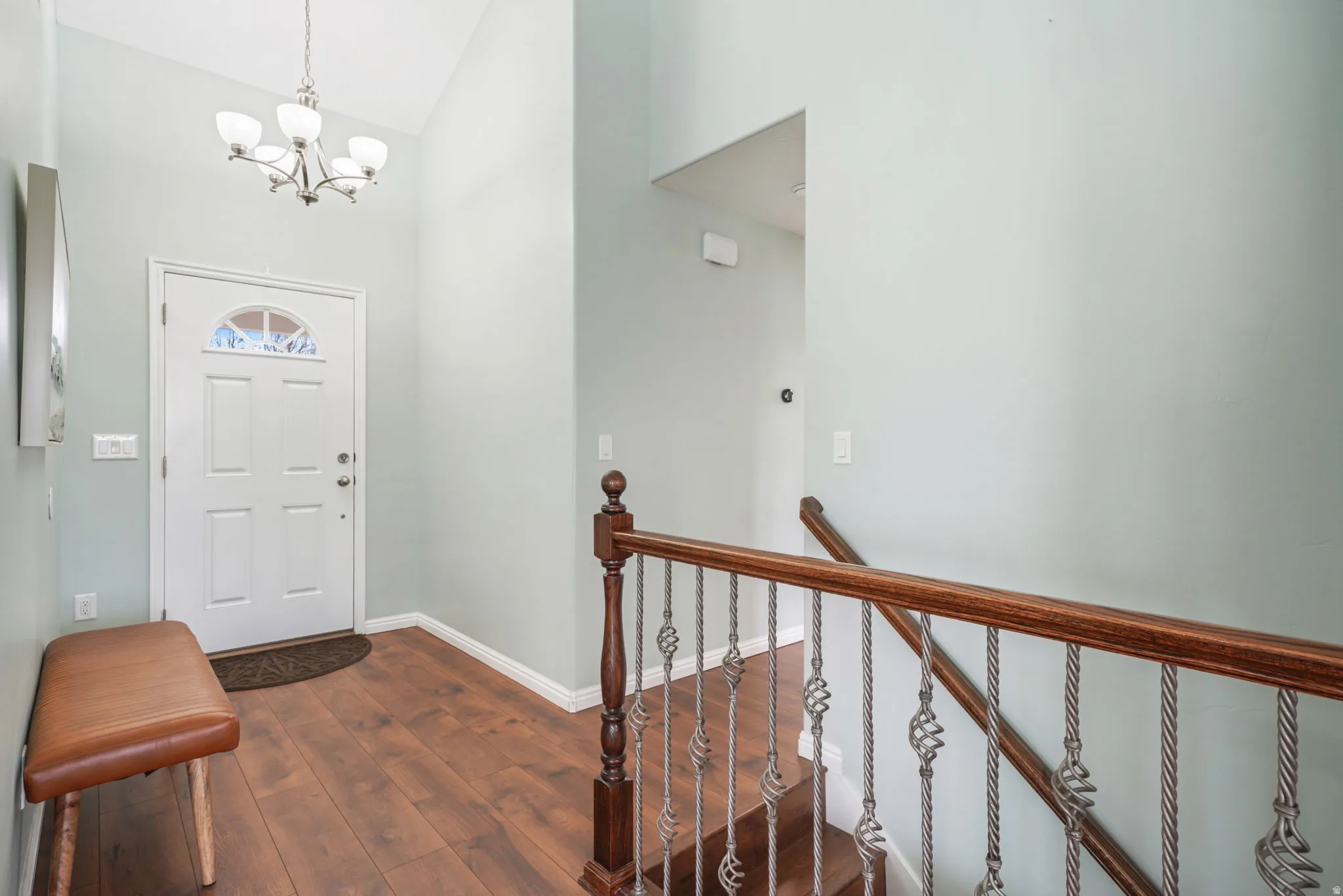 Foyer with dark wood finished floors, vaulted ceiling, and suspended lighting