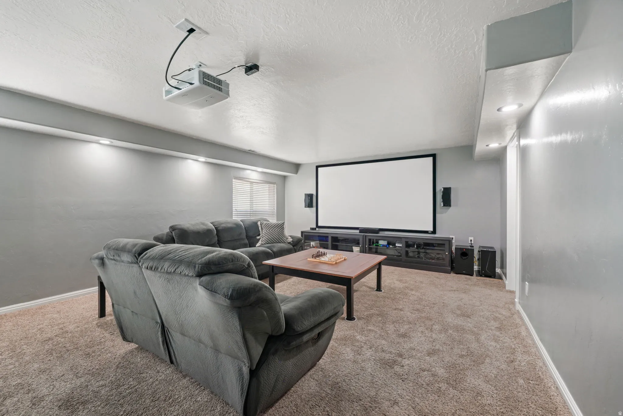 Home theater room featuring a textured ceiling and carpet flooring