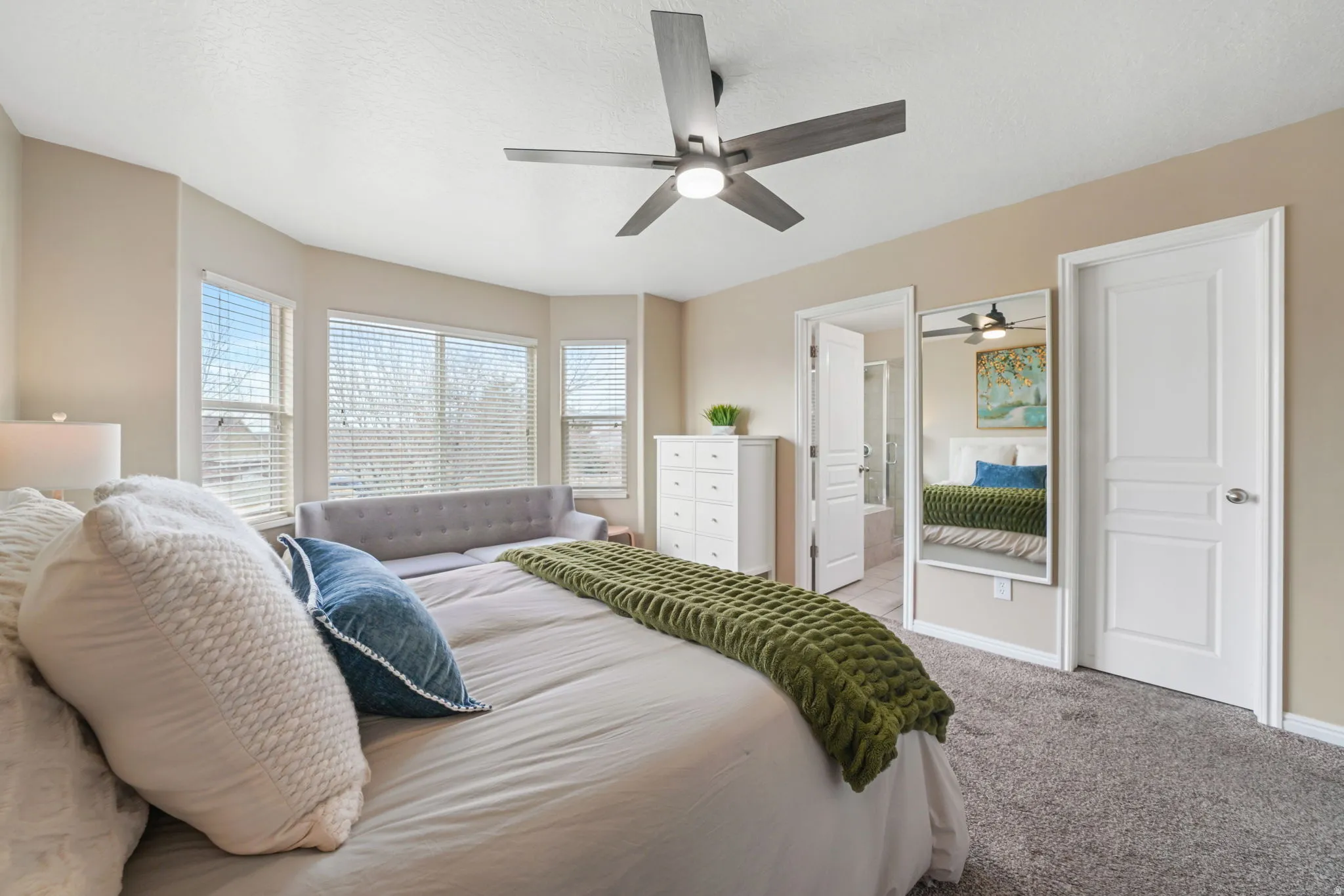 Bedroom featuring carpet floors, a ceiling fan, and ensuite bath