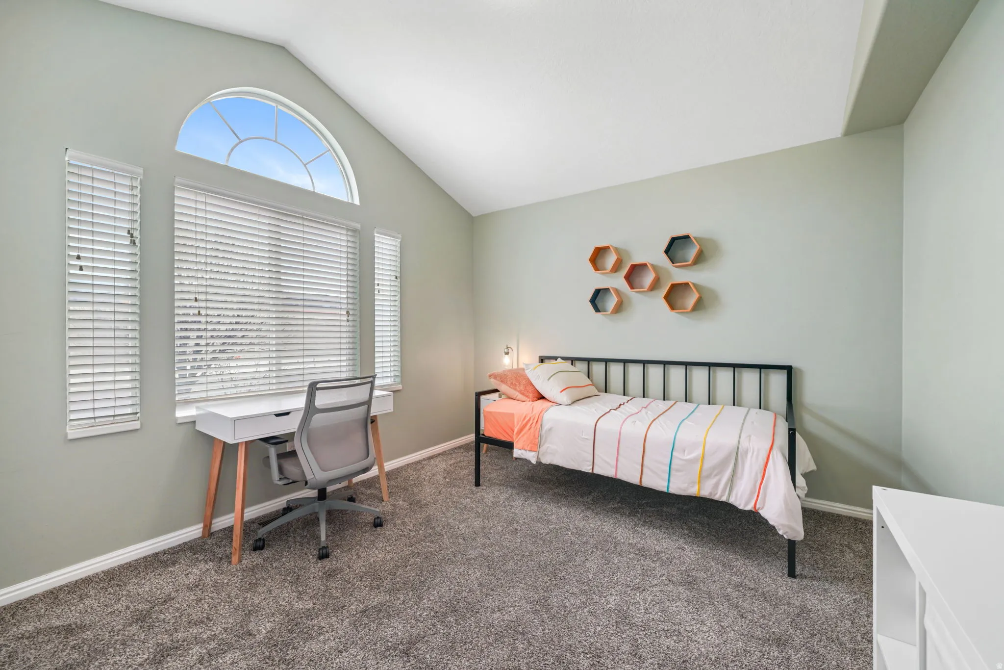 Carpeted bedroom with vaulted ceiling and baseboards